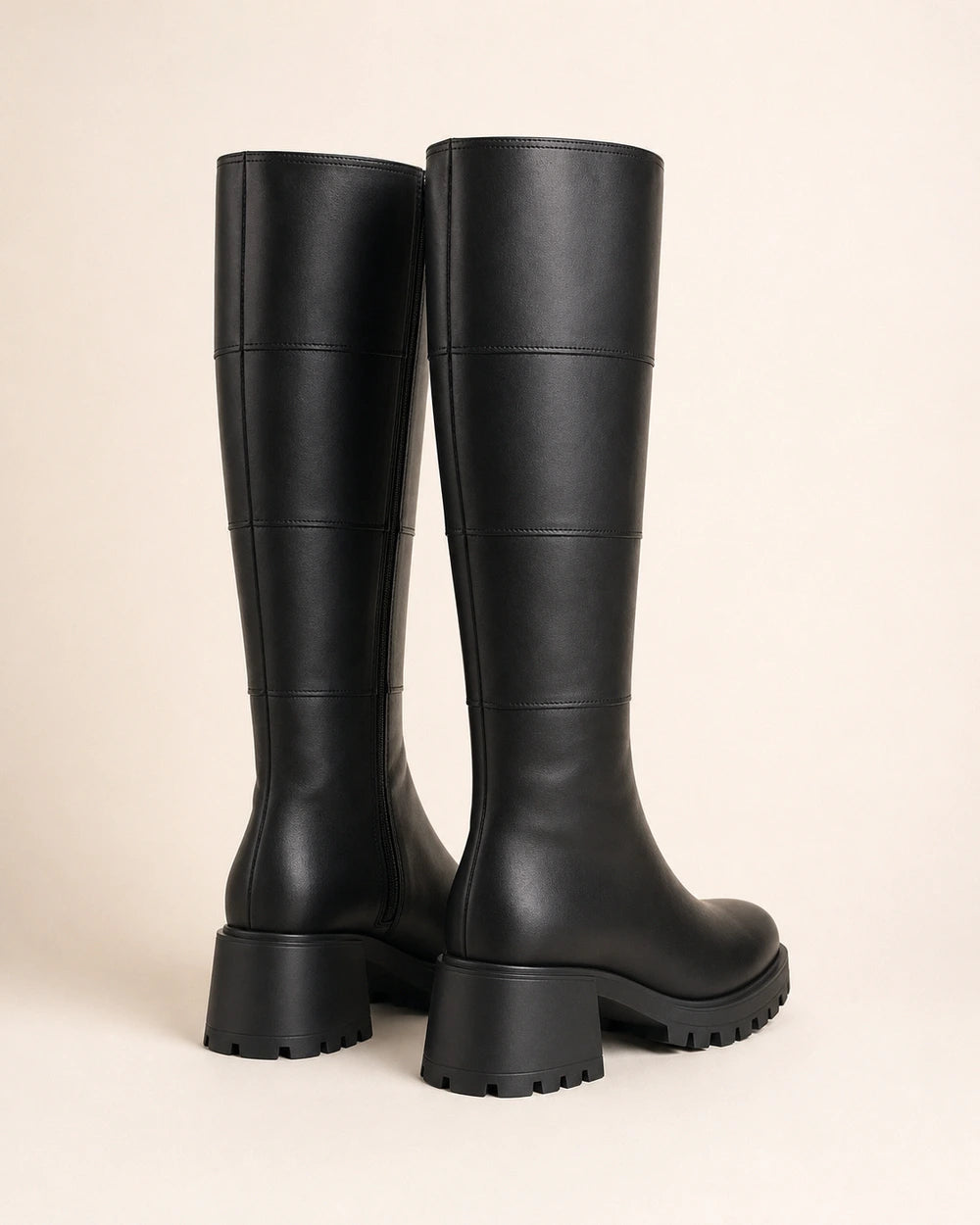 Women's black chunky knee-high boots, rear three-quarter view.